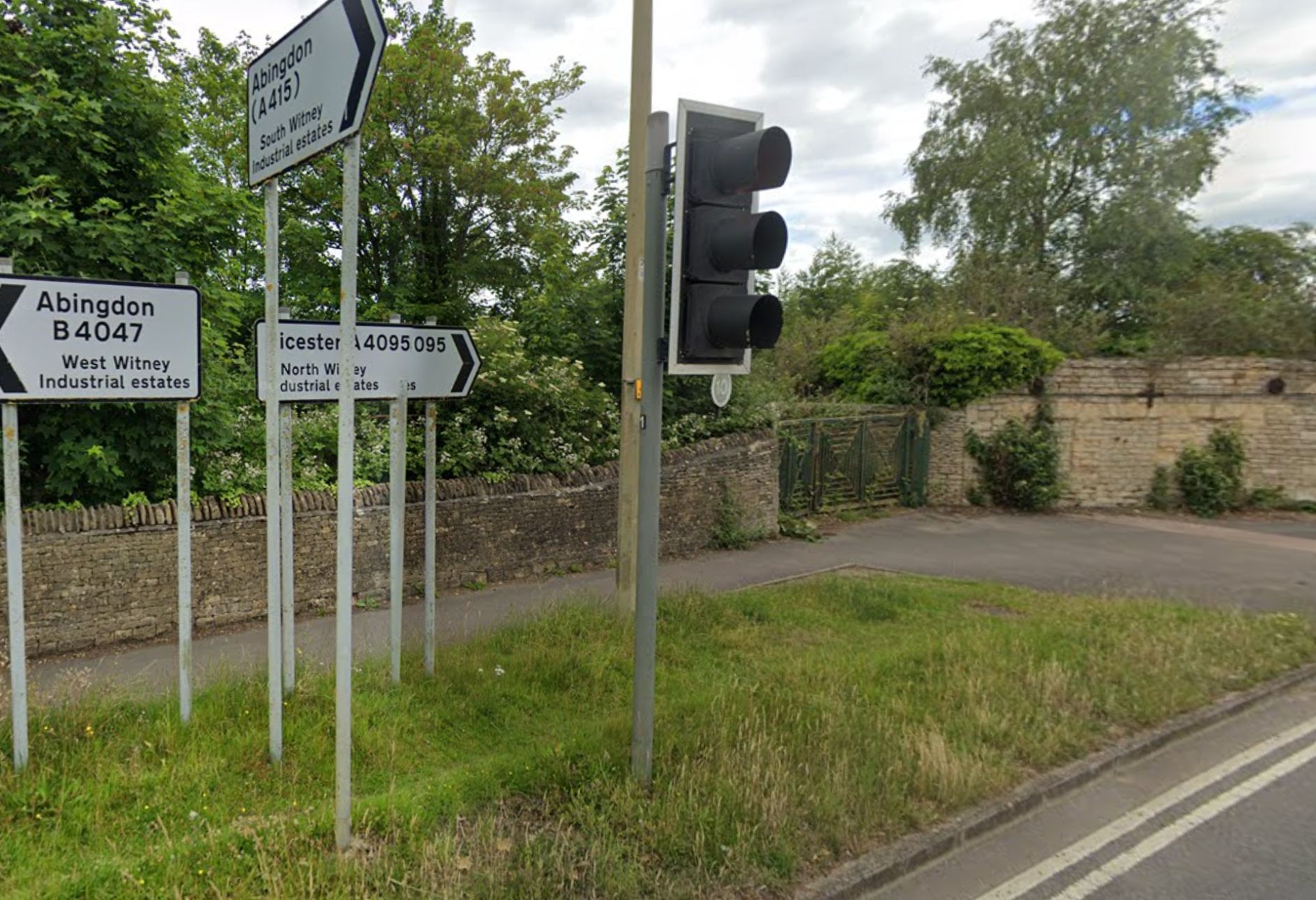 Traffic light, pavement, and green gates behind